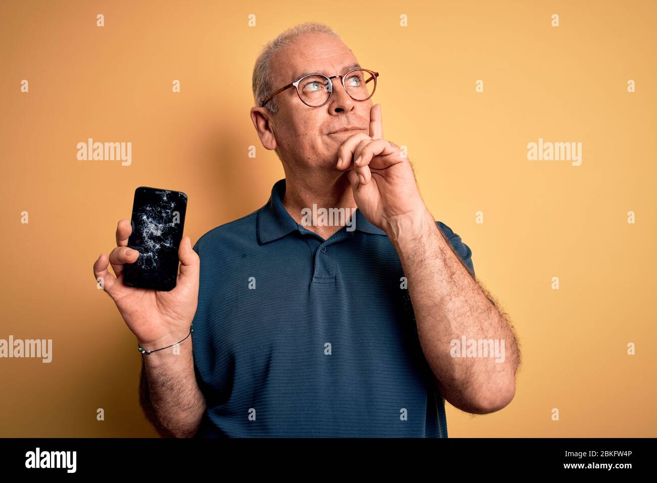 Middle age man holding broken smartphone showing cracked screen over ...