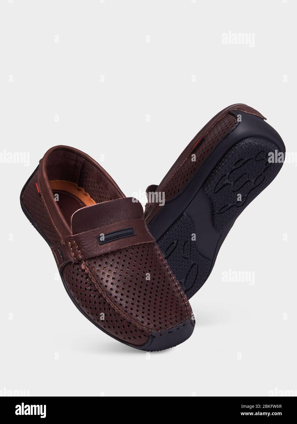 Men's brown leather summer loafers with perforation and black sole. Isolated on a white