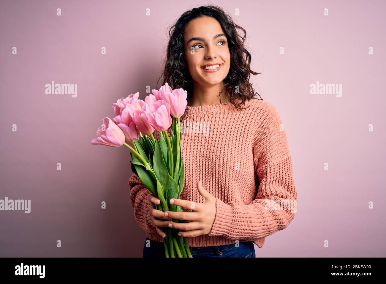Young beautiful romantic woman with curly hair holding bouquet of pink ...