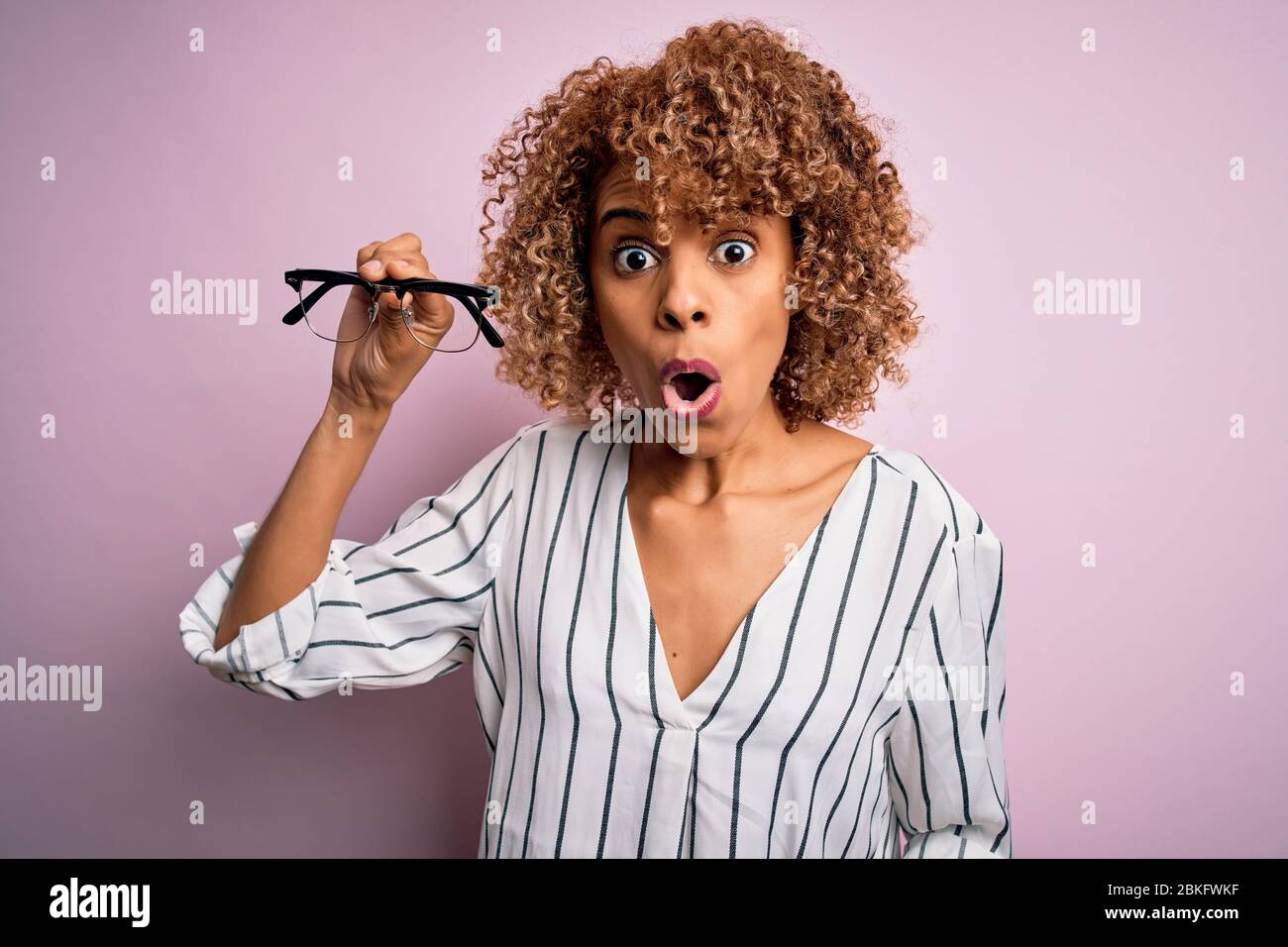 African american optical woman with curly hair holding glasses over ...