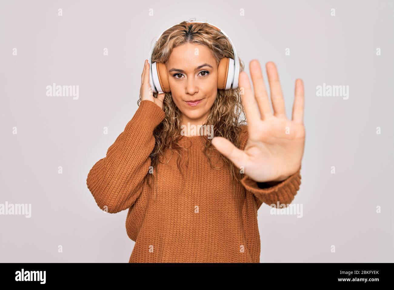 Young beautiful blonde woman listening to music using headphones over ...