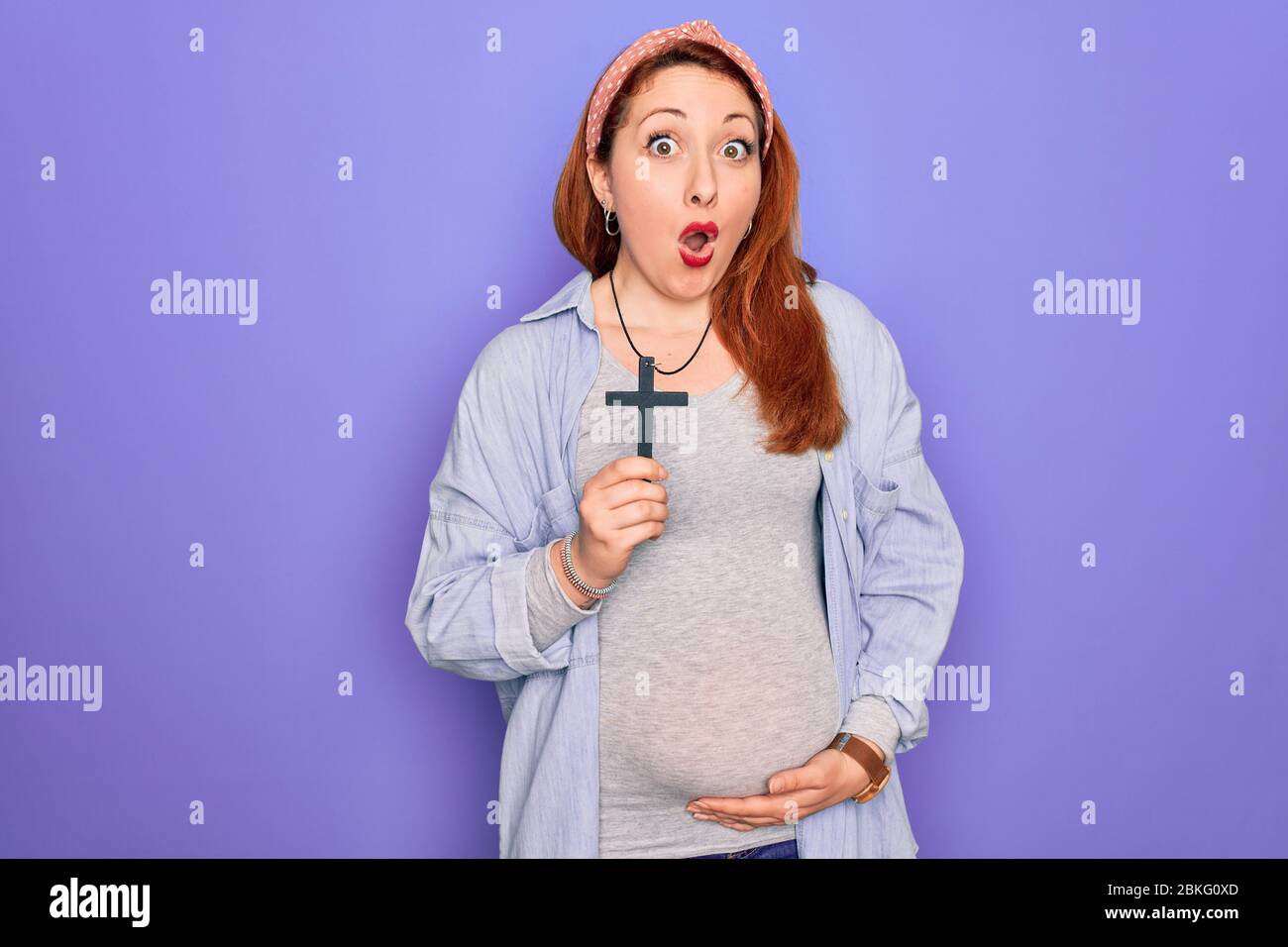 Young beautiful redhead pregnant woman expecting baby holding christian ...