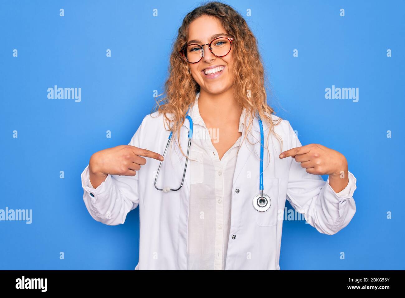Young beautiful blonde doctor woman with blue eyes wearing coat and ...