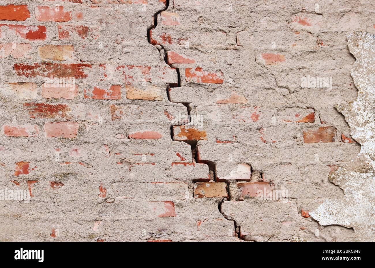 symbol for a damage, crack in an old brick wall, background with copy space Stock Photo