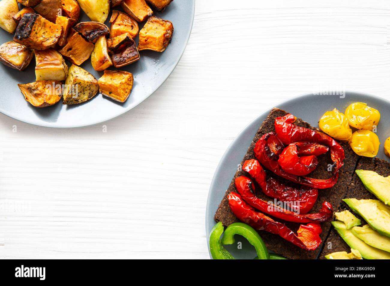 Roasted sweet potatoes (batata) and grilled paprika and avocado healthy toast on white table background, copy space, top view. Stock Photo