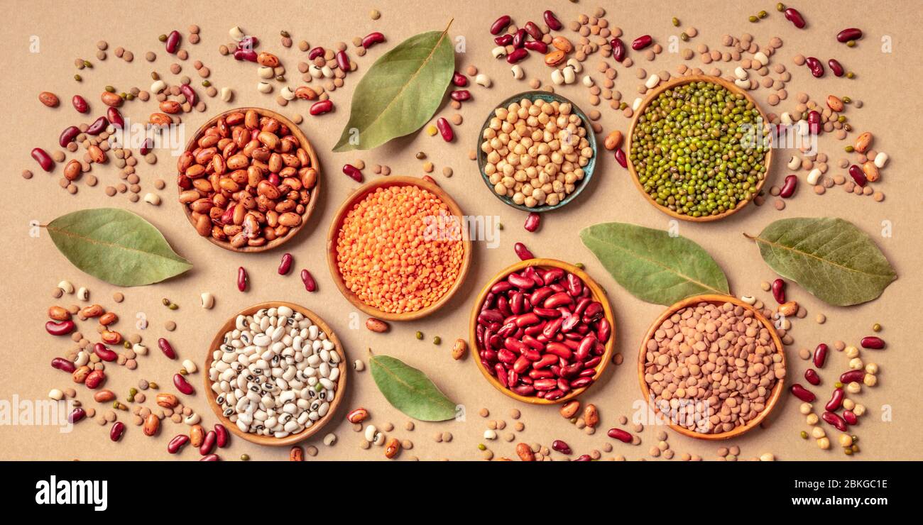 Legumes assortment, overhead panoramic shot on a brown background