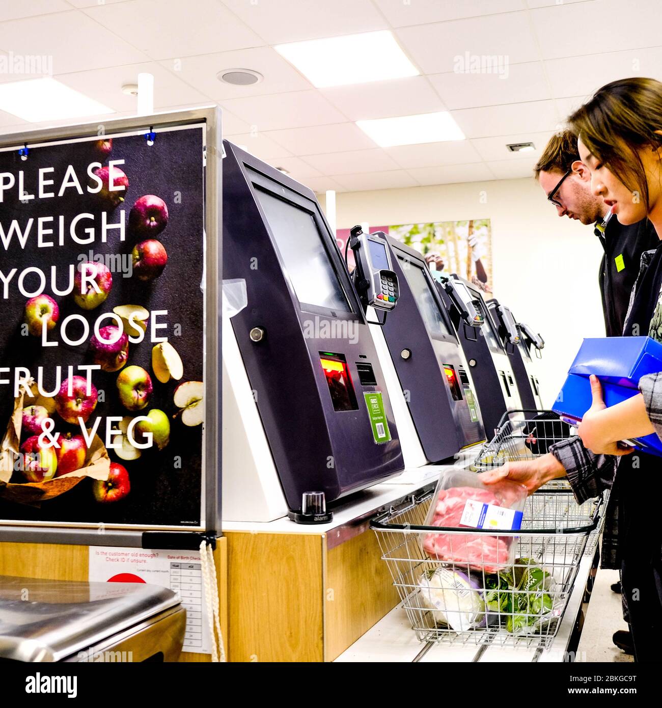 Young Woman With A Shopping Basket Of Food Paying At A Self Service Automated Till Or Paypoint Stock Photo