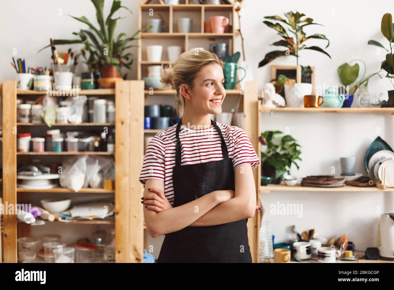 Smiling girl in black apron and T-shirt happily looking aside with ...