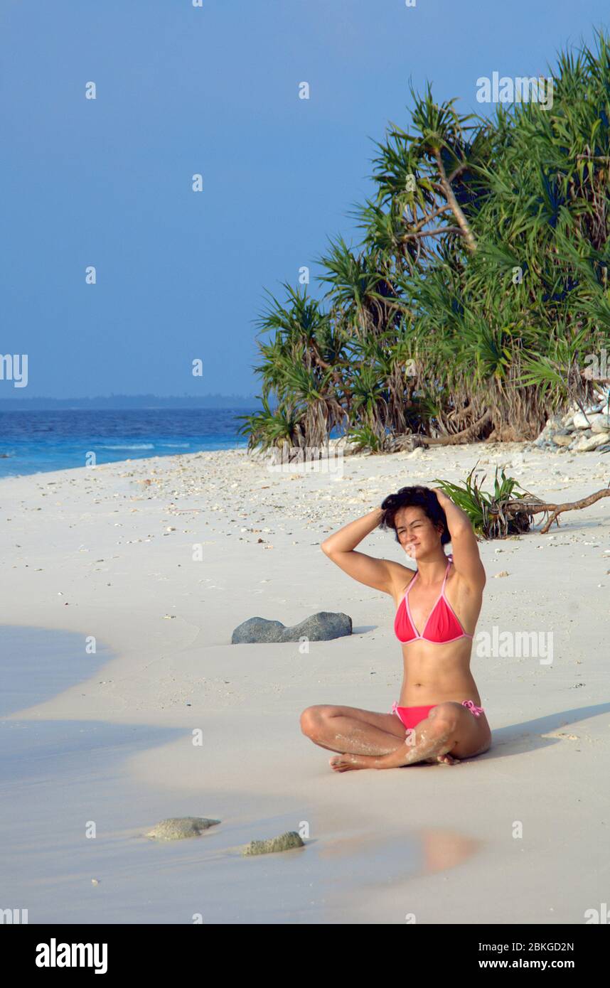 Frau sitzt am Strand, Frau blickt aufs Meer Stock Photo