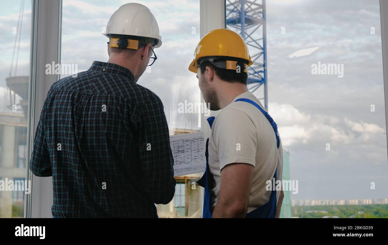 Engineer and worker looking at blueprint. Stock Photo
