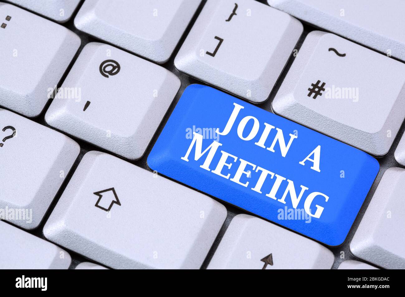 A keyboard with words JOIN A MEETING in white lettering on a blue enter key. Apps for video call conferencing concept. England, UK, Britain Stock Photo