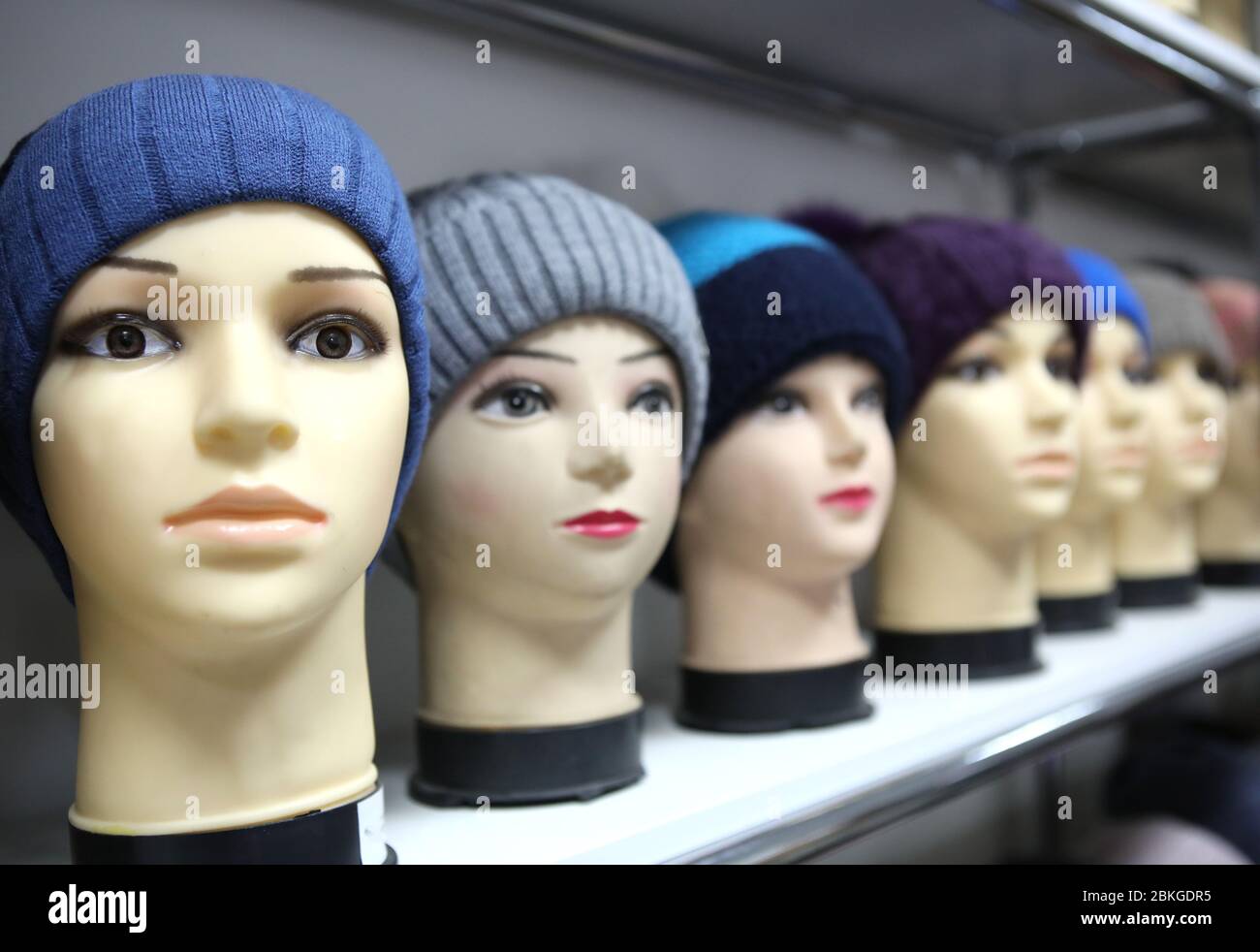 Mannequin heads in knitted hats and scarves. Mannequins female heads in hats and scarfs close up. Woolen knitted caps and scarves. Female headdresses. Stock Photo