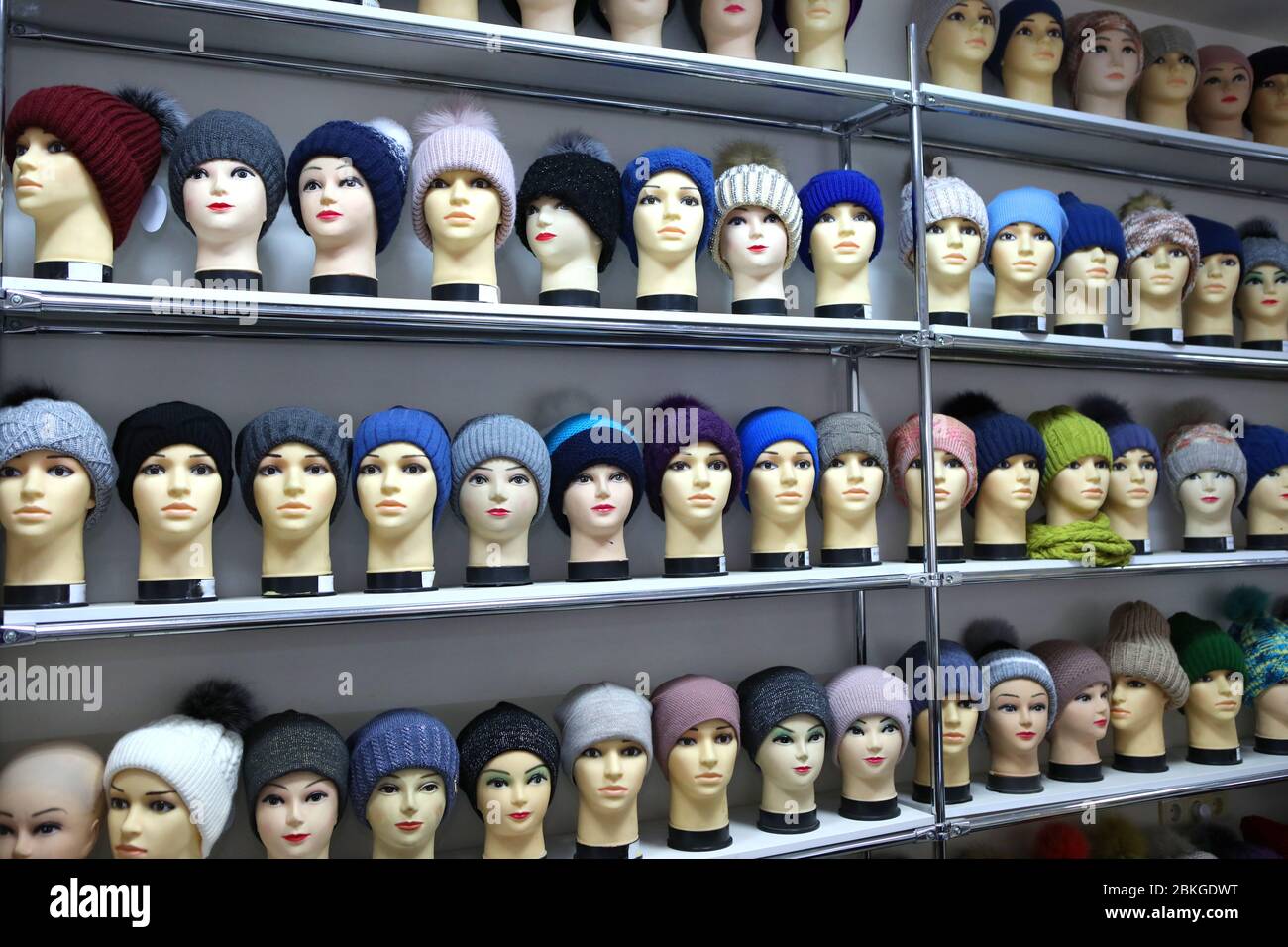 Mannequin heads in knitted hats and scarves. Mannequins female heads in hats and scarfs close up. Woolen knitted caps and scarves. Female headdresses. Stock Photo