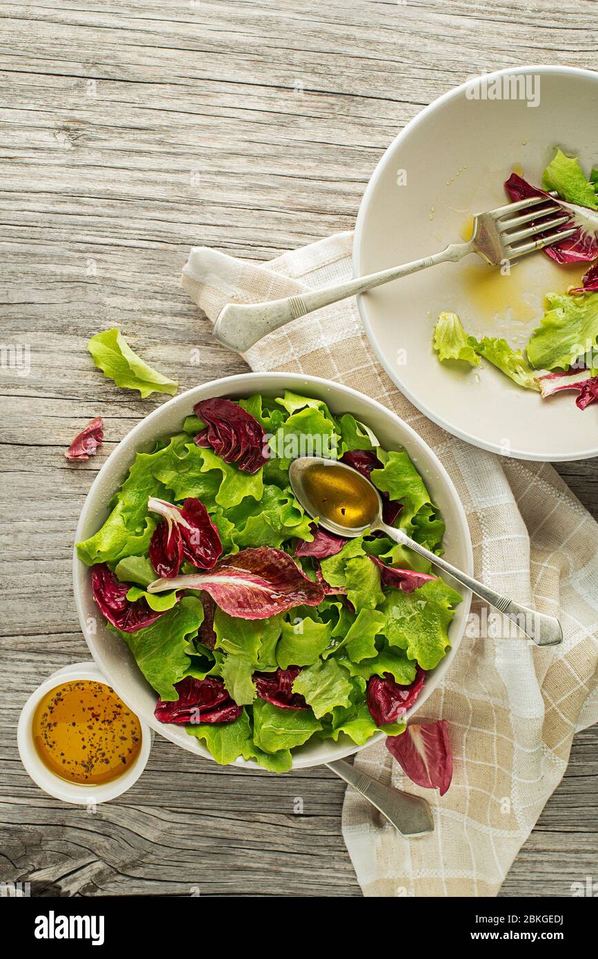 Healthy red and green lettuce salad meal on wooden table background. Eating fresh radicchio and young lettuce with dressing sauce Stock Photo