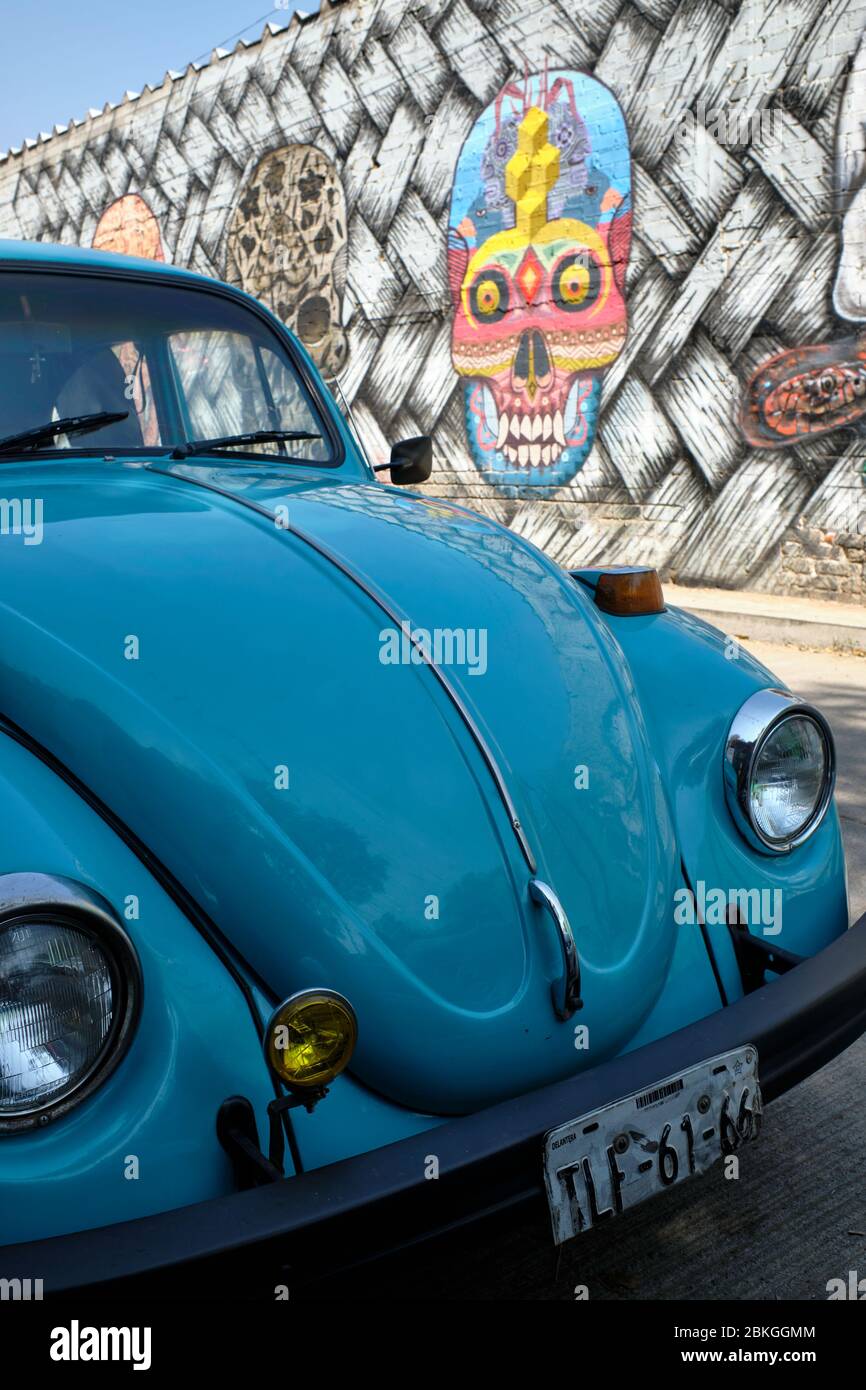 Volkswagen beetle parked next to a wall painted with murals referring to the 'Day of the Dead' festivities. Stock Photo