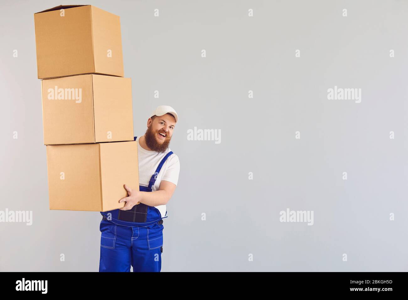 Funny delivery loader man with a cardboard box on a gray background