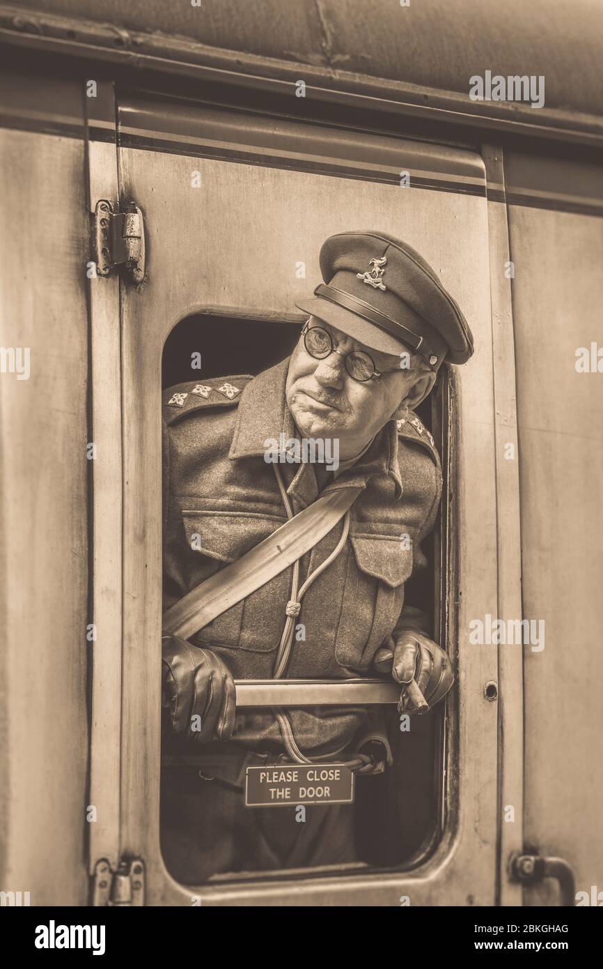 Sepia close up, 1940s man as WW2 Home Guard officer Captain Mainwaring (Arthur Lowe lookalike) looking out vintage train window Severn Valley Railway. Stock Photo
