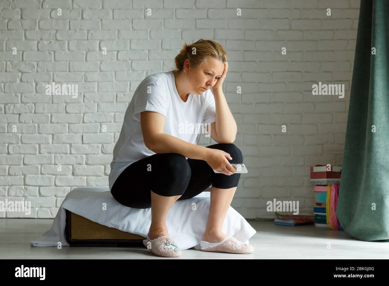 Upset stressed woman holding cellphone disgusted with message she received home background. Sad looking human face expression emotion feeling reaction Stock Photo