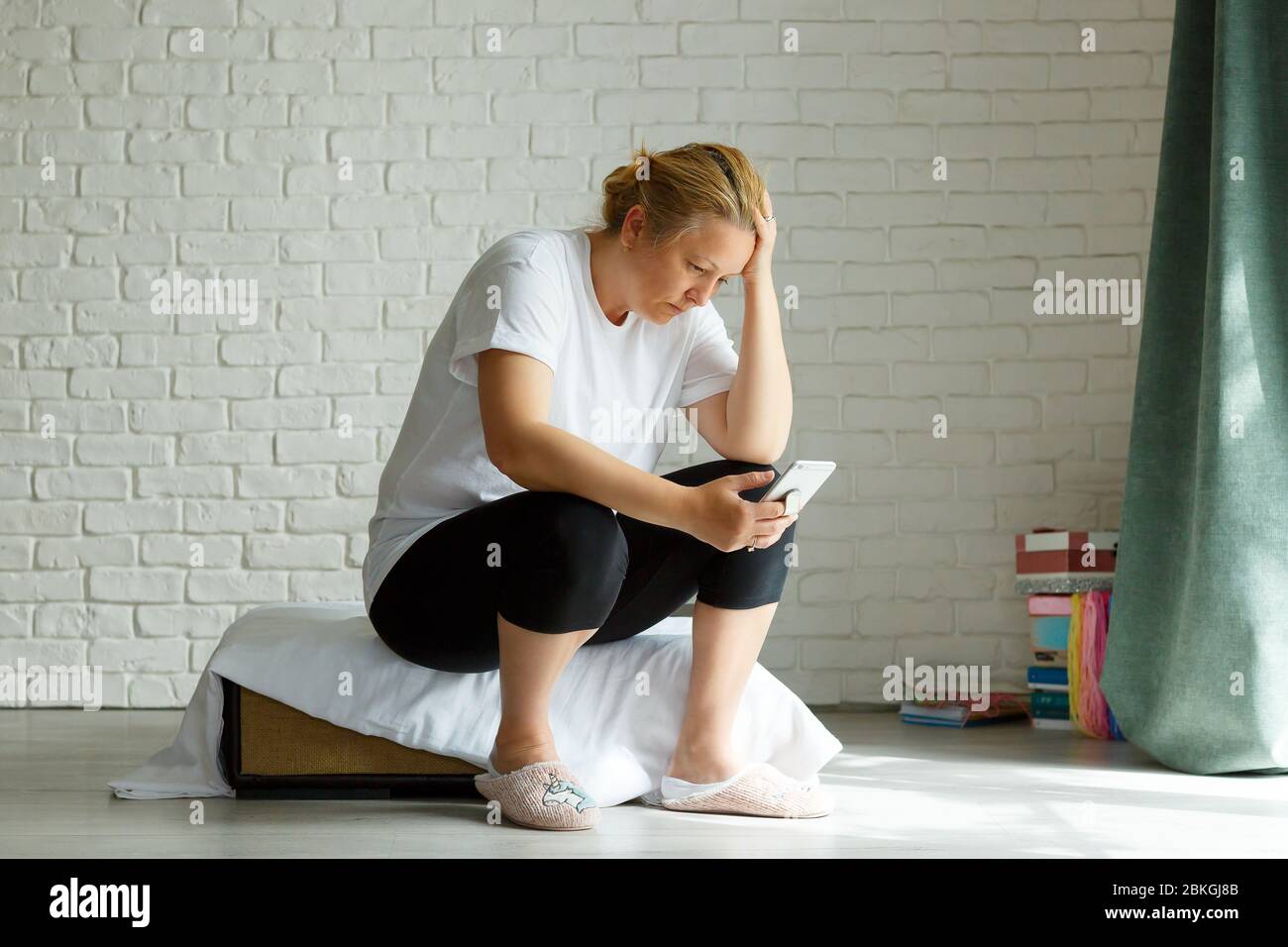 Upset stressed woman holding cellphone disgusted with message she received home background. Sad looking human face expression emotion feeling reaction Stock Photo