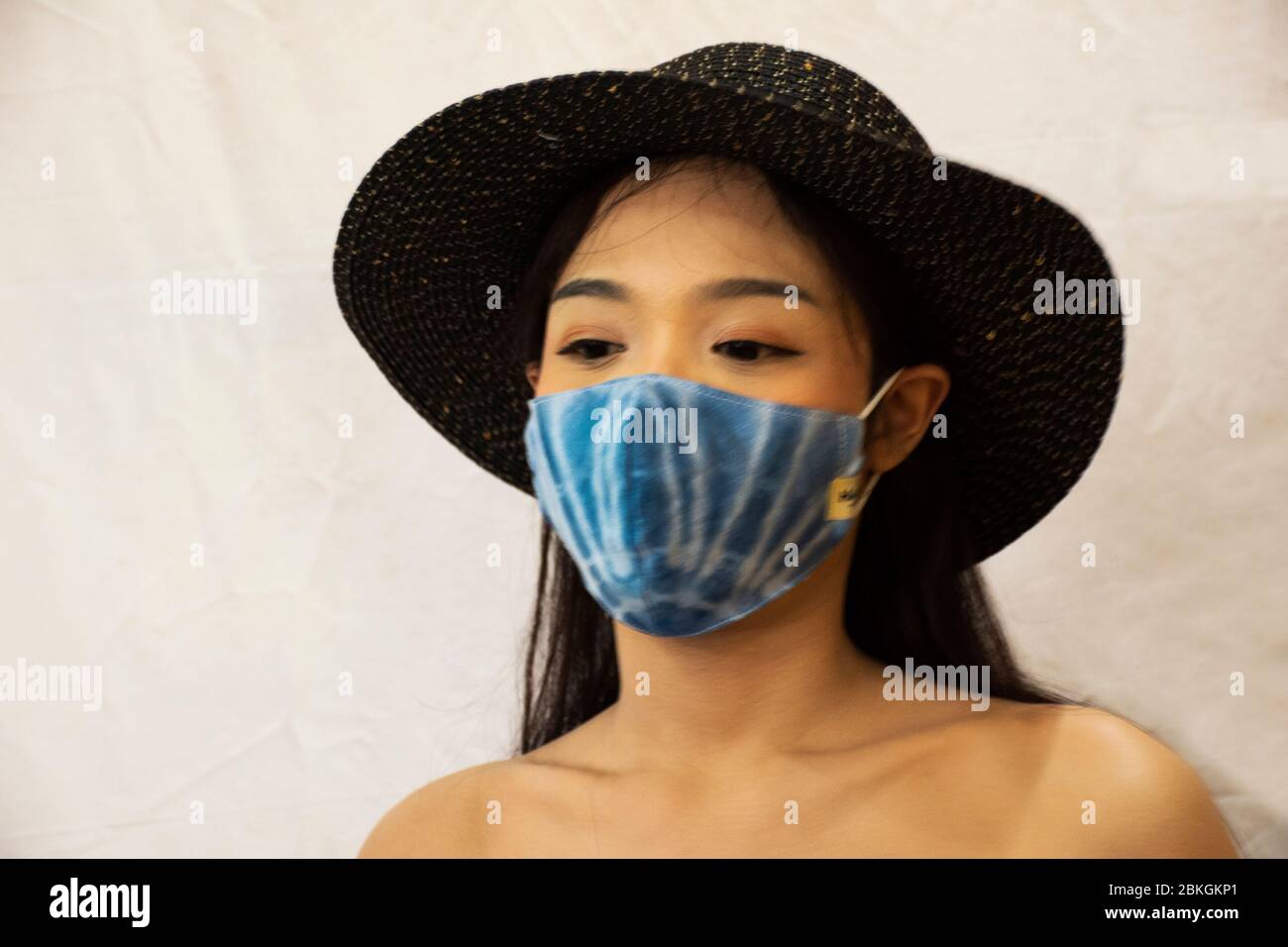 Thai women wear handmade indigo fabric mask with hat and posing portrait for take photo at studio while Coronavirus COVID 19 outbreak and PM 2.5 Dust Stock Photo