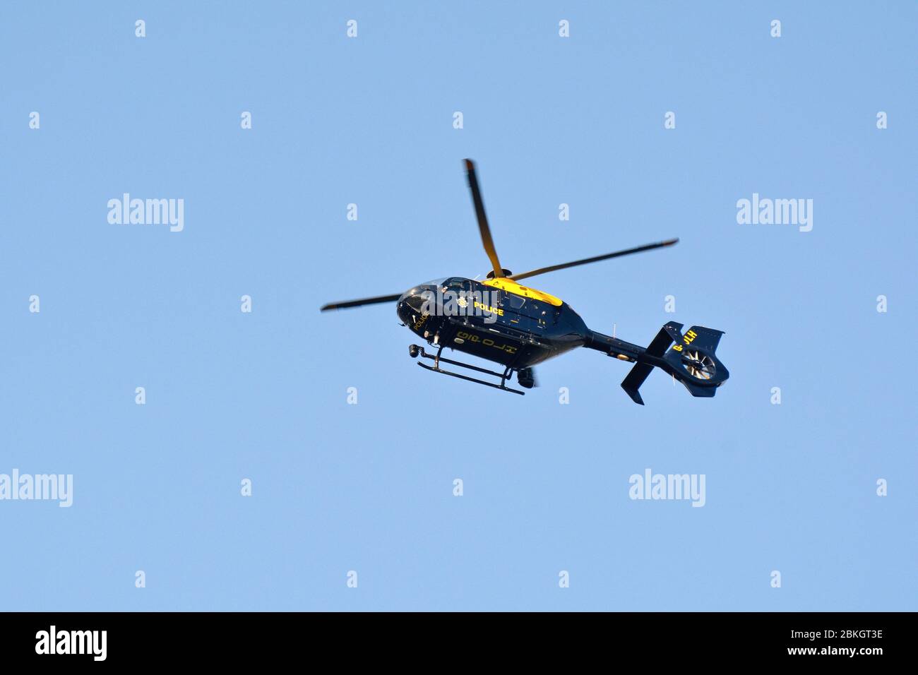 A National Police Air Service helicopter hovering above against a clear blue sky Stock Photo