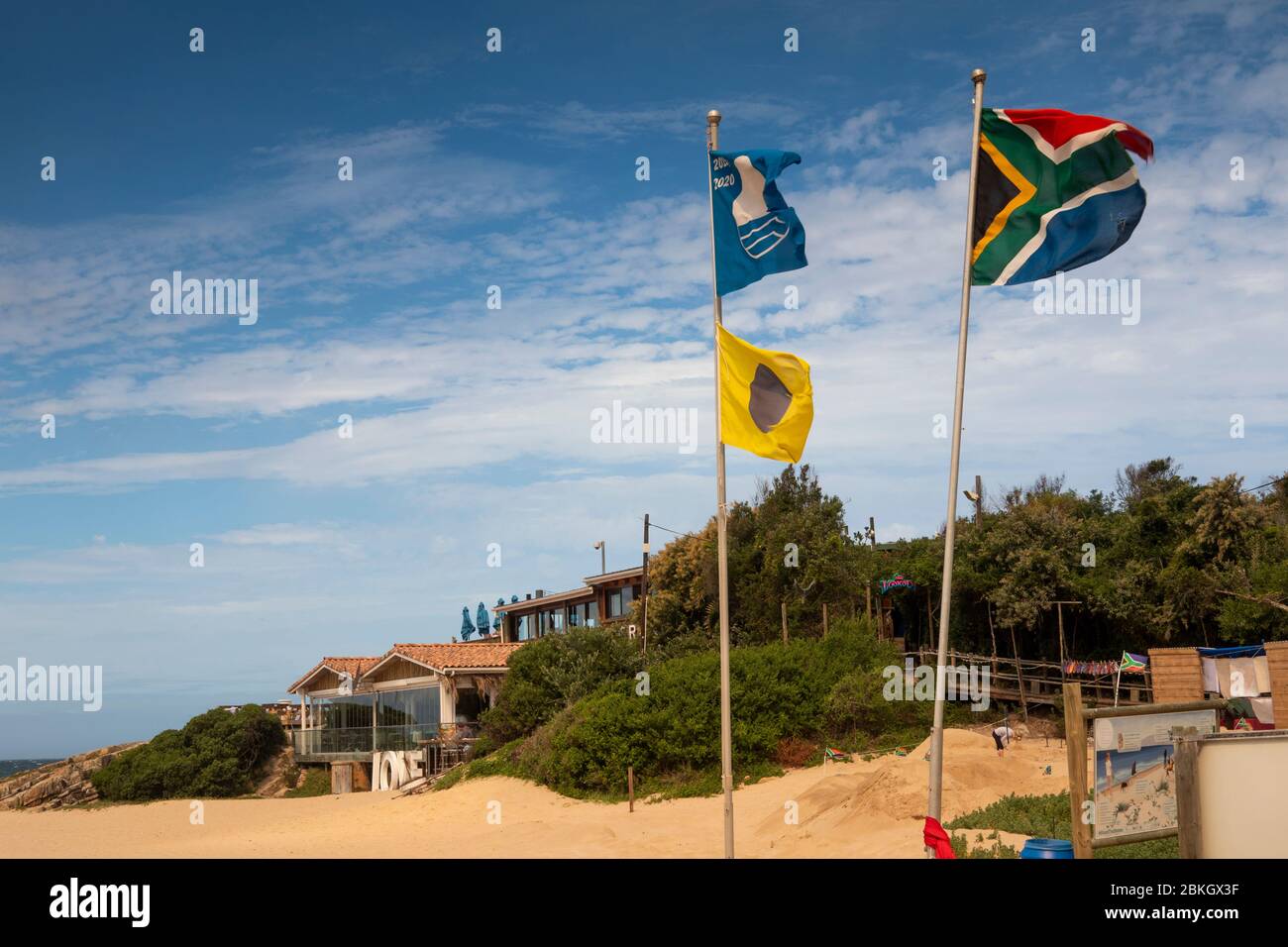 South Africa, Western Cape, Plettenberg Bay, Hill Street, blue flag flying at Lookout Beach with yellow and black lifeguard flag and national flag Stock Photo