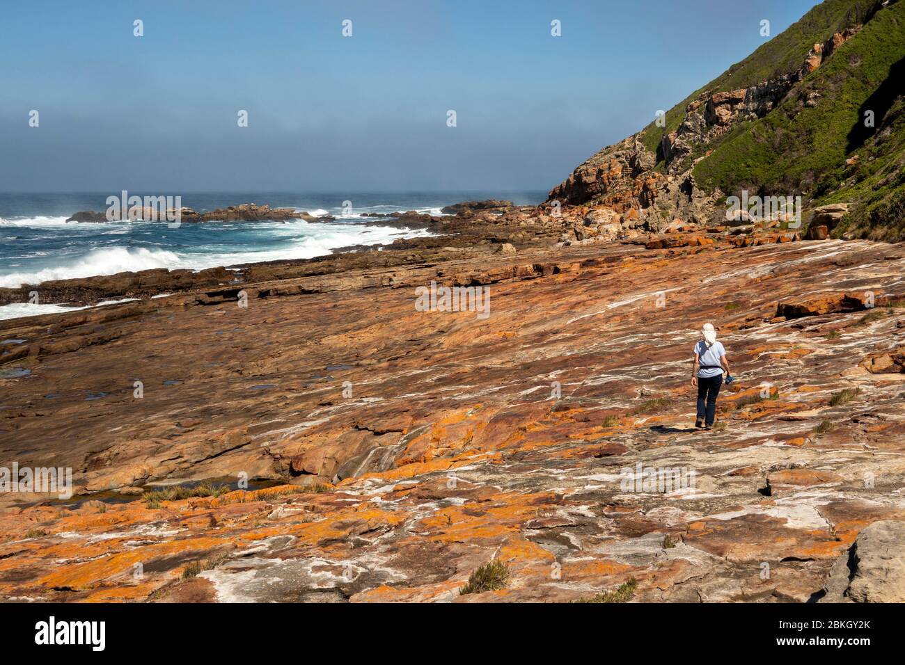 South Africa, Western Cape, Plettenberg Bay, Robberg Nature Reserve, Cape Seal, tourist on rocky path above coastline with heavy sea Stock Photo