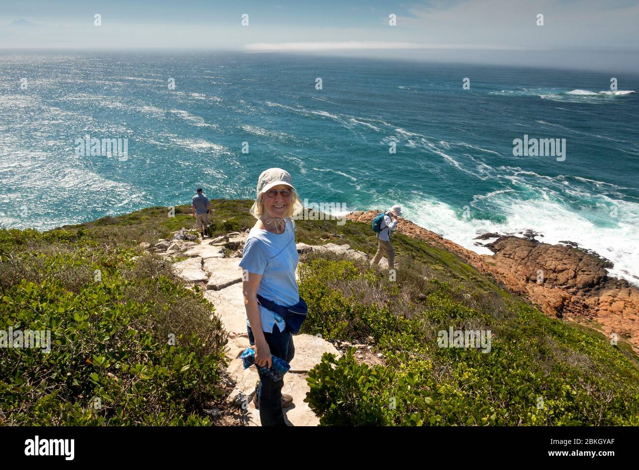 South Africa, Western Cape, Plettenberg Bay, Robberg Nature Reserve, Cape Seal, tourists on path above rocky coastline Stock Photo