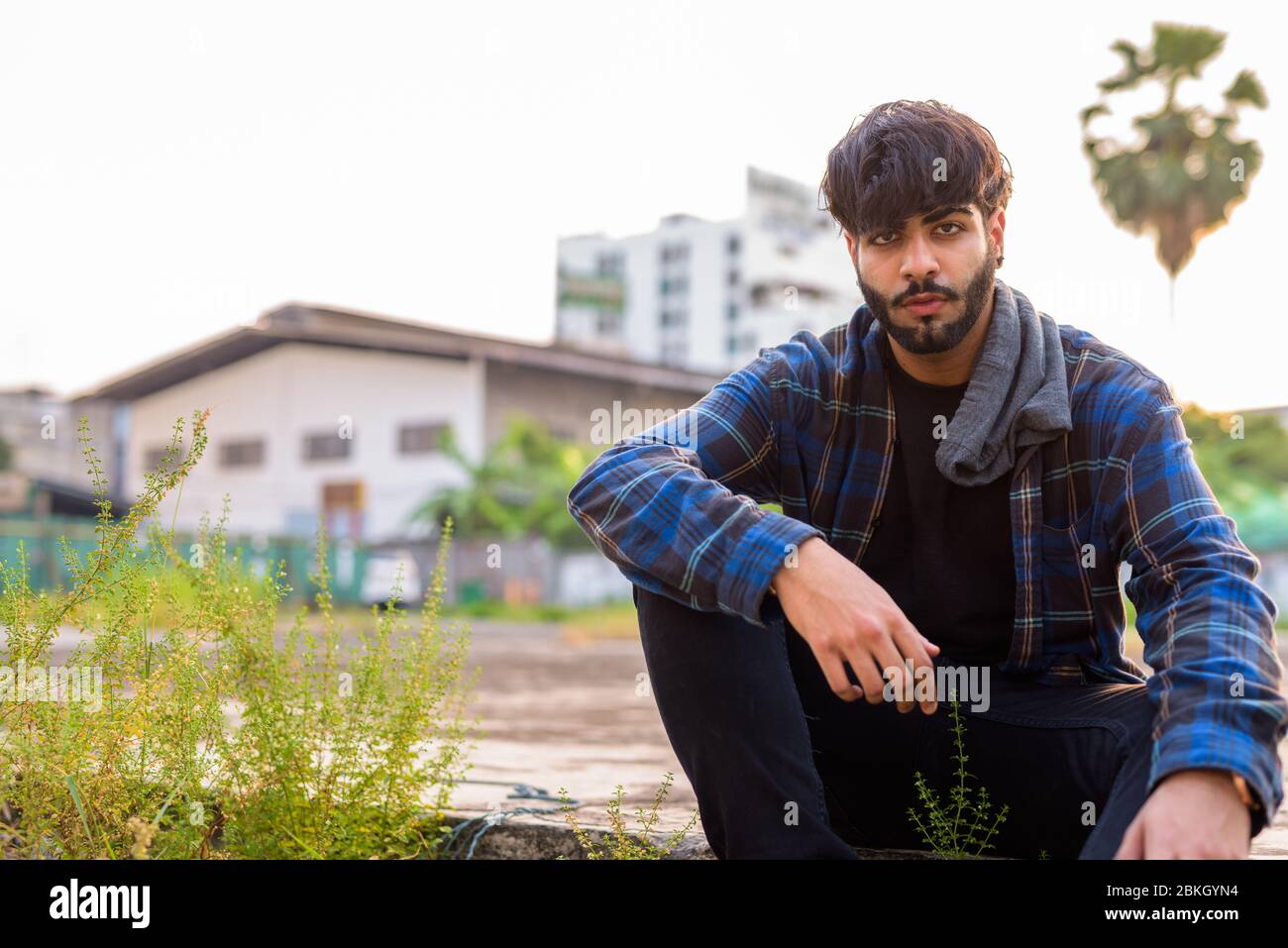 Young handsome bearded Indian hipster man sitting in urban streets Stock  Photo - Alamy