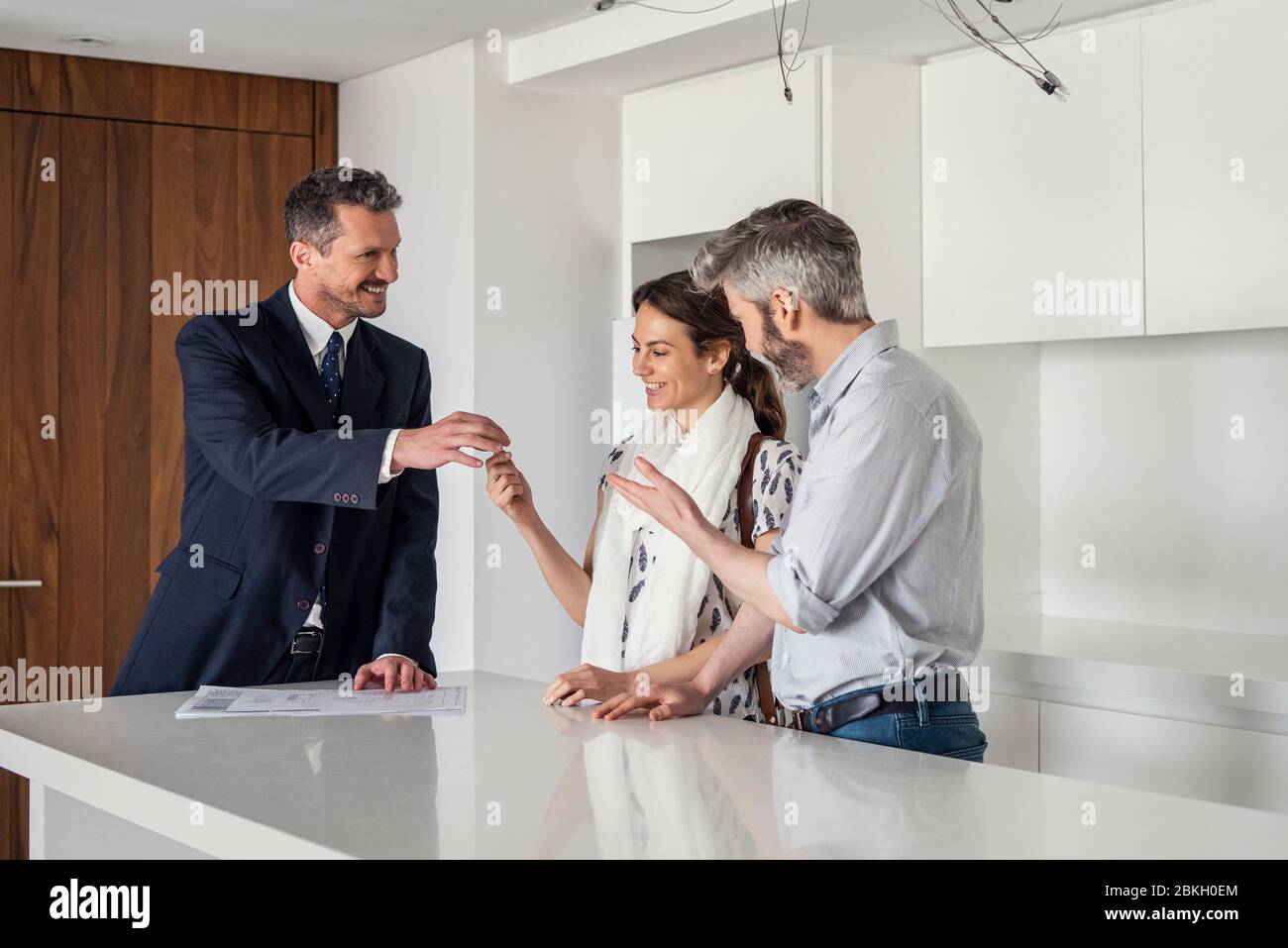 Real estate agent giving house keys to couple Stock Photo - Alamy