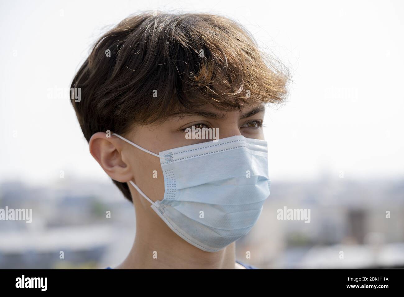Close up of teenage boy wearing blue surgical mask outdoors Stock Photo ...