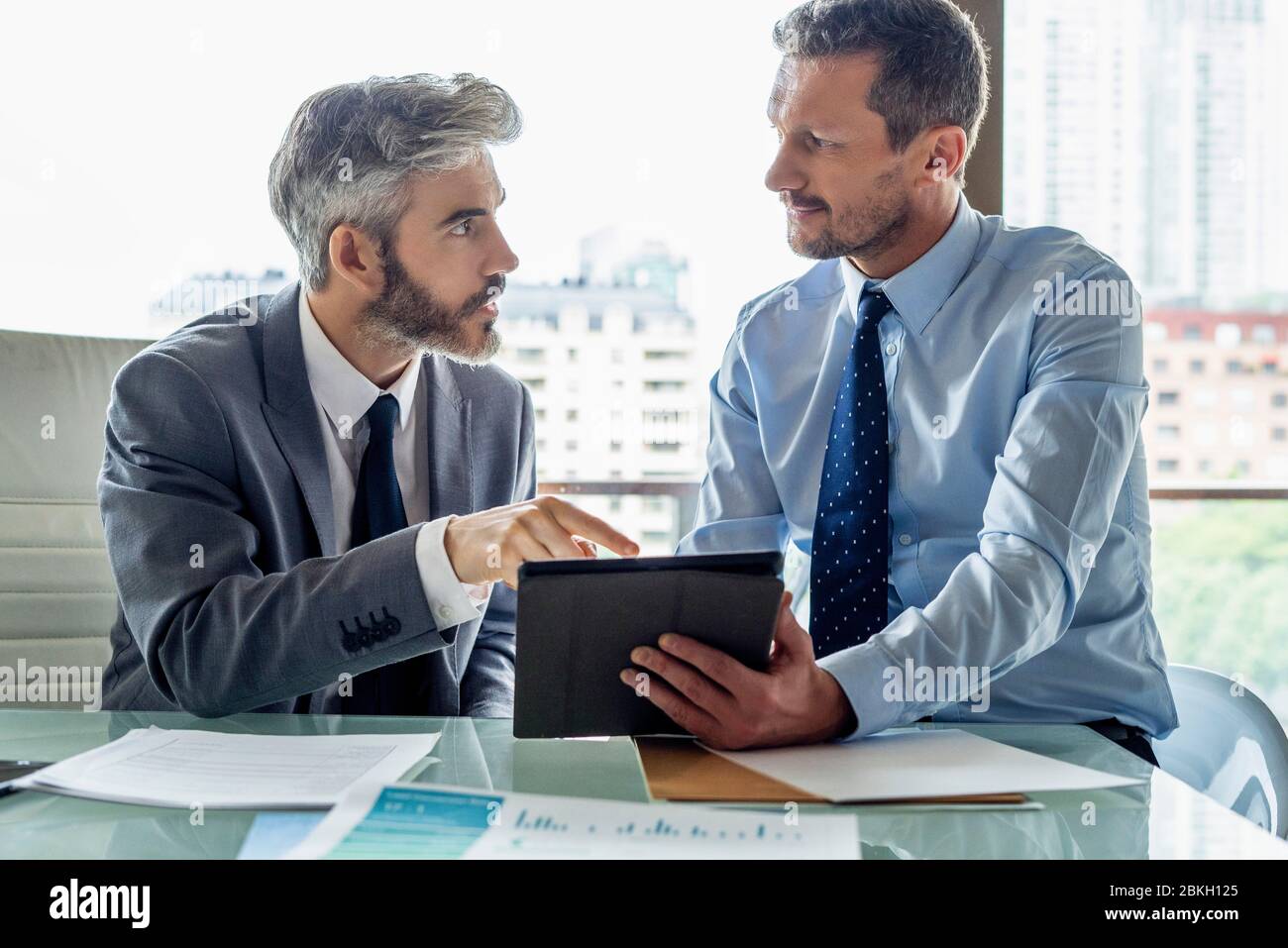 Businessmen discussing over digital tablet Stock Photo