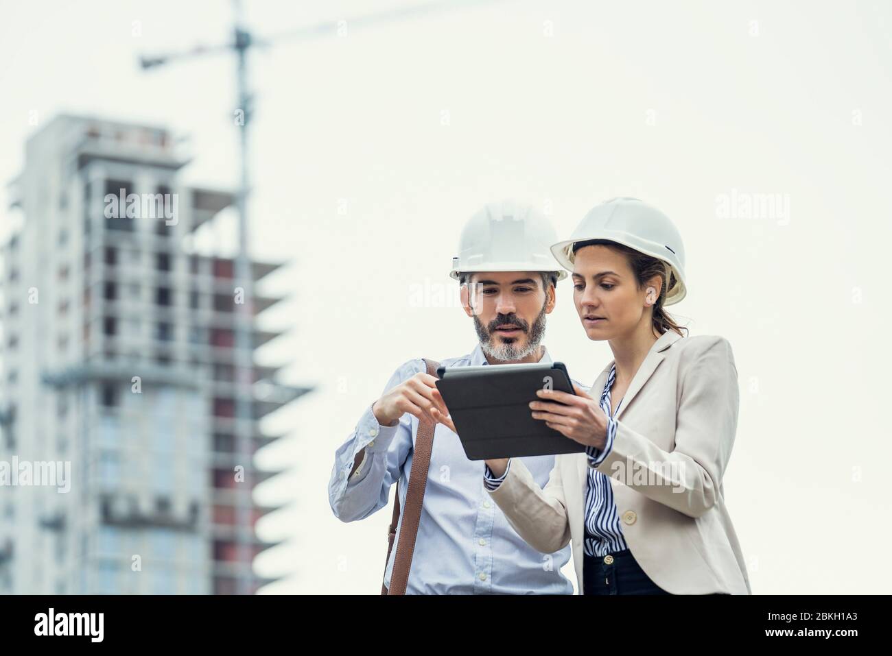 Architects using digital tablet at construction site Stock Photo