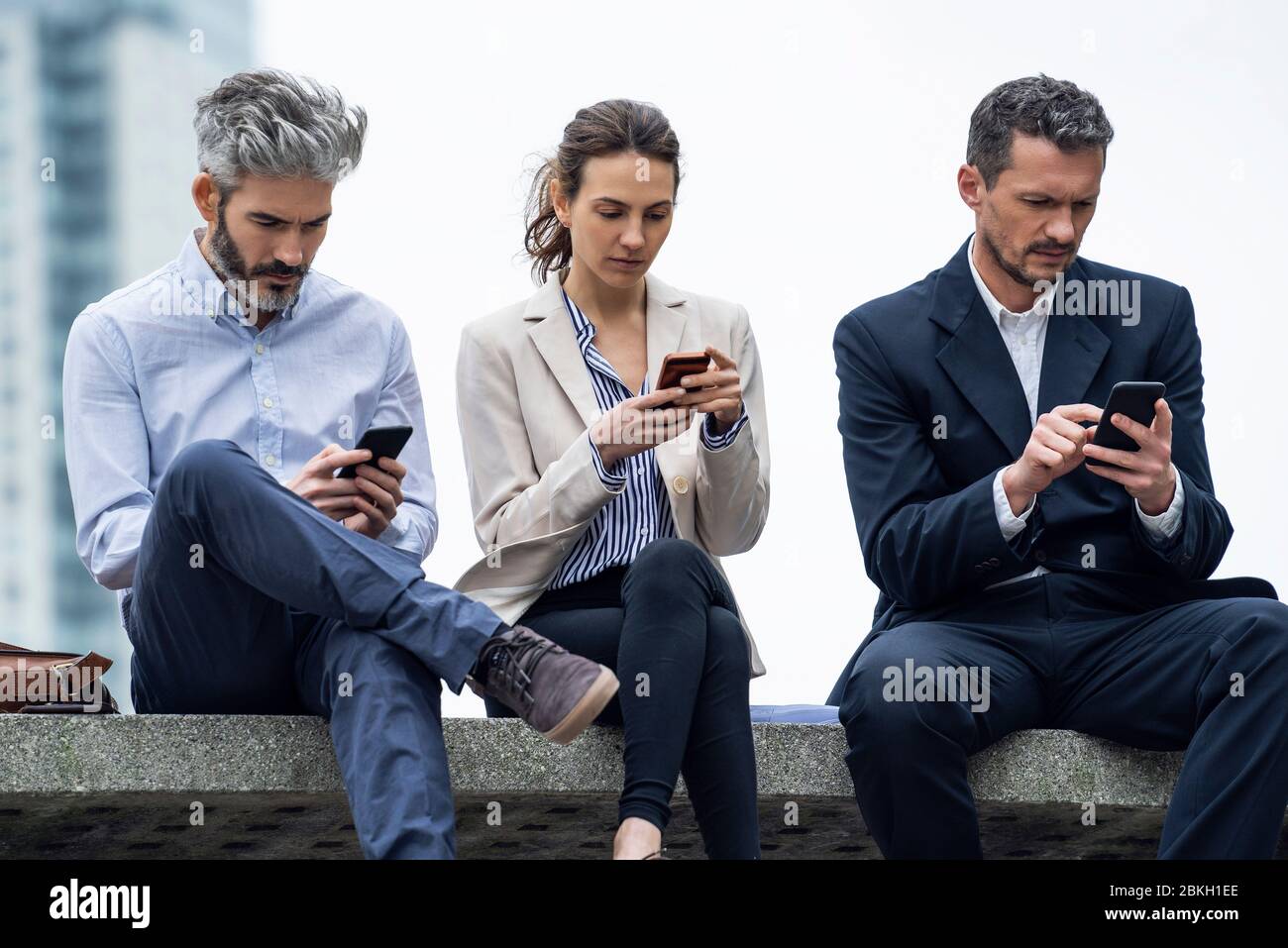 Business people using smartphones in public park Stock Photo