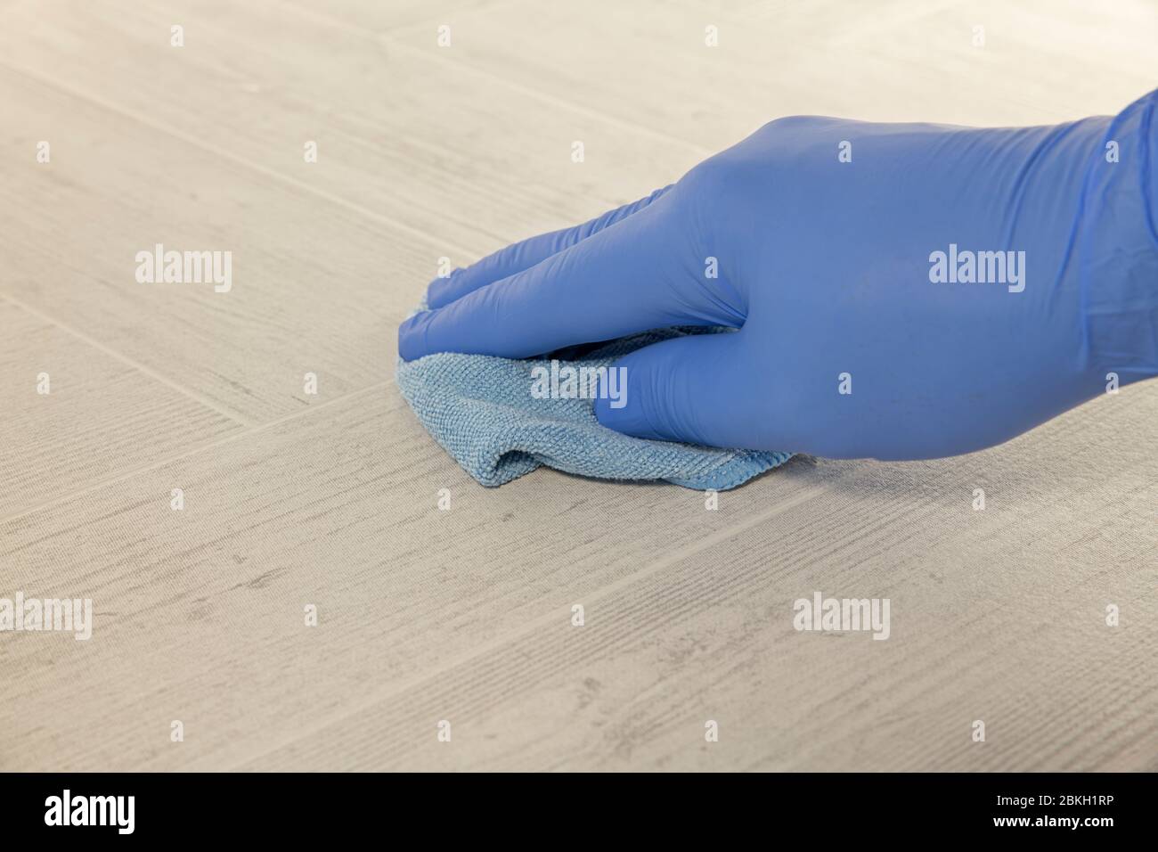 hand with blue rubber glove cleaning a floor with a wiping pad Stock Photo