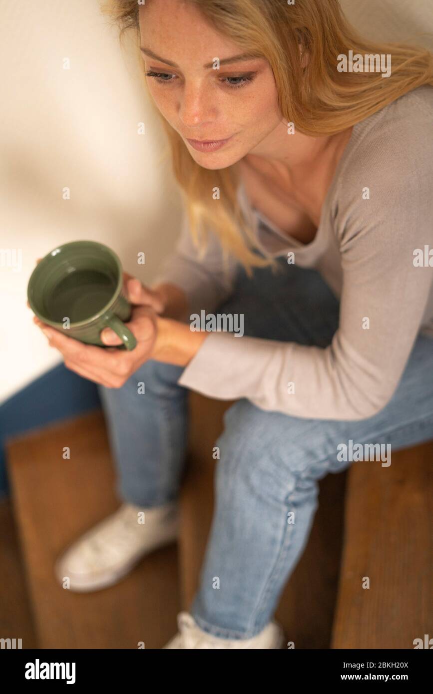 Young woman holding cup while sitting on steps Stock Photo