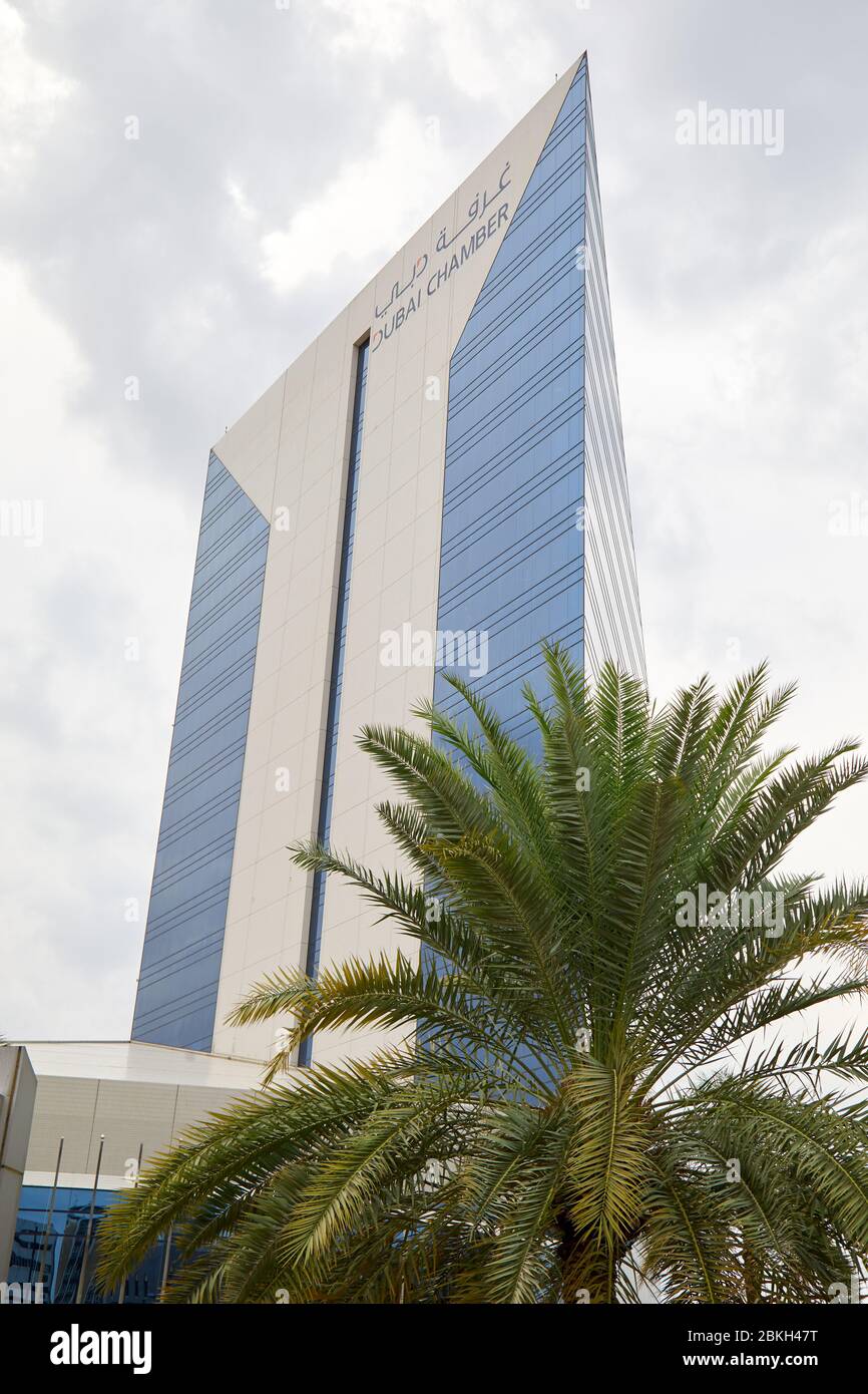DUBAI, UNITED ARAB EMIRATES - NOVEMBER 21, 2019: Dubai Chamber of Commerce and Industry building and palm tree in a cloudy day Stock Photo
