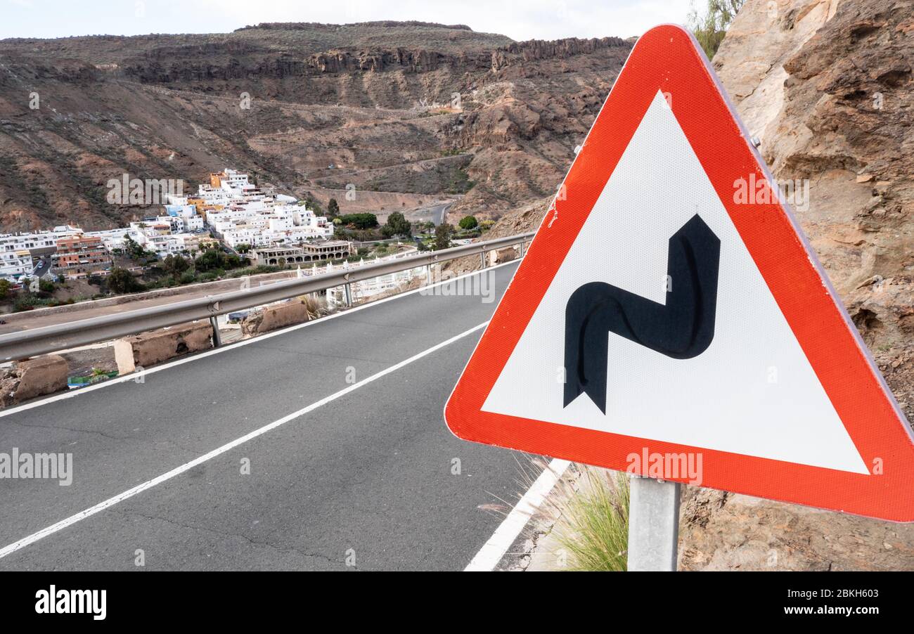 Traffic Warning sign: Bend Ahead. A triangular road sign giving notice of bends ahead on a hillside road high in the hills of Gran Canaria. Stock Photo