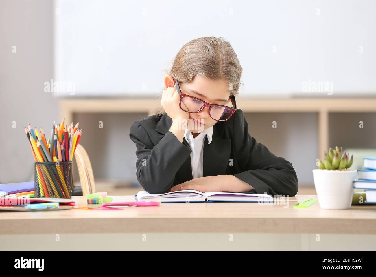 Bored little schoolgirl at desk in classroom Stock Photo - Alamy