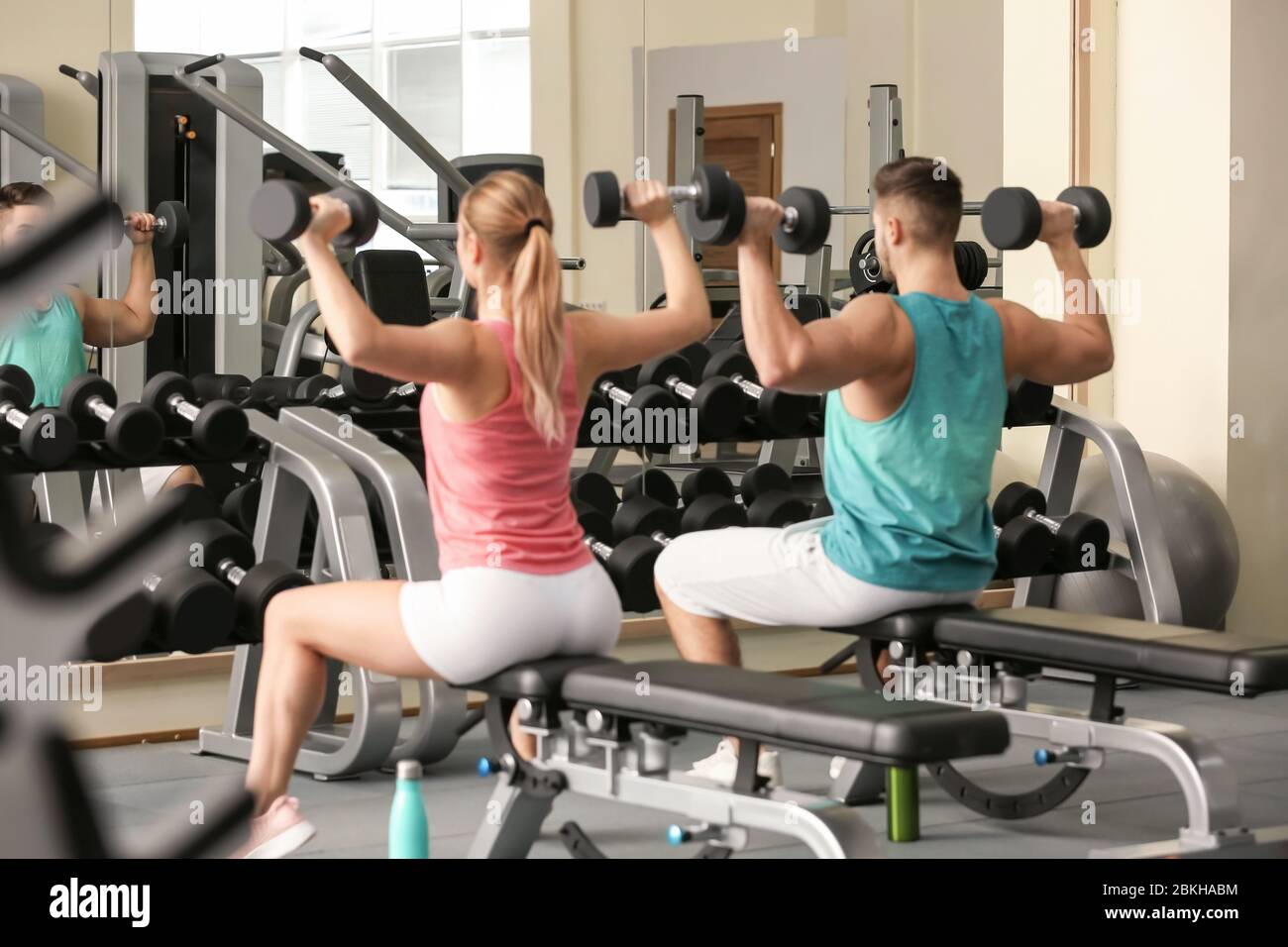 Sporty young couple training with dumbbells in gym Stock Photo - Alamy