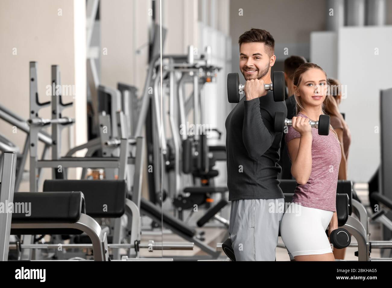 Sporty young couple training with dumbbells in gym Stock Photo - Alamy