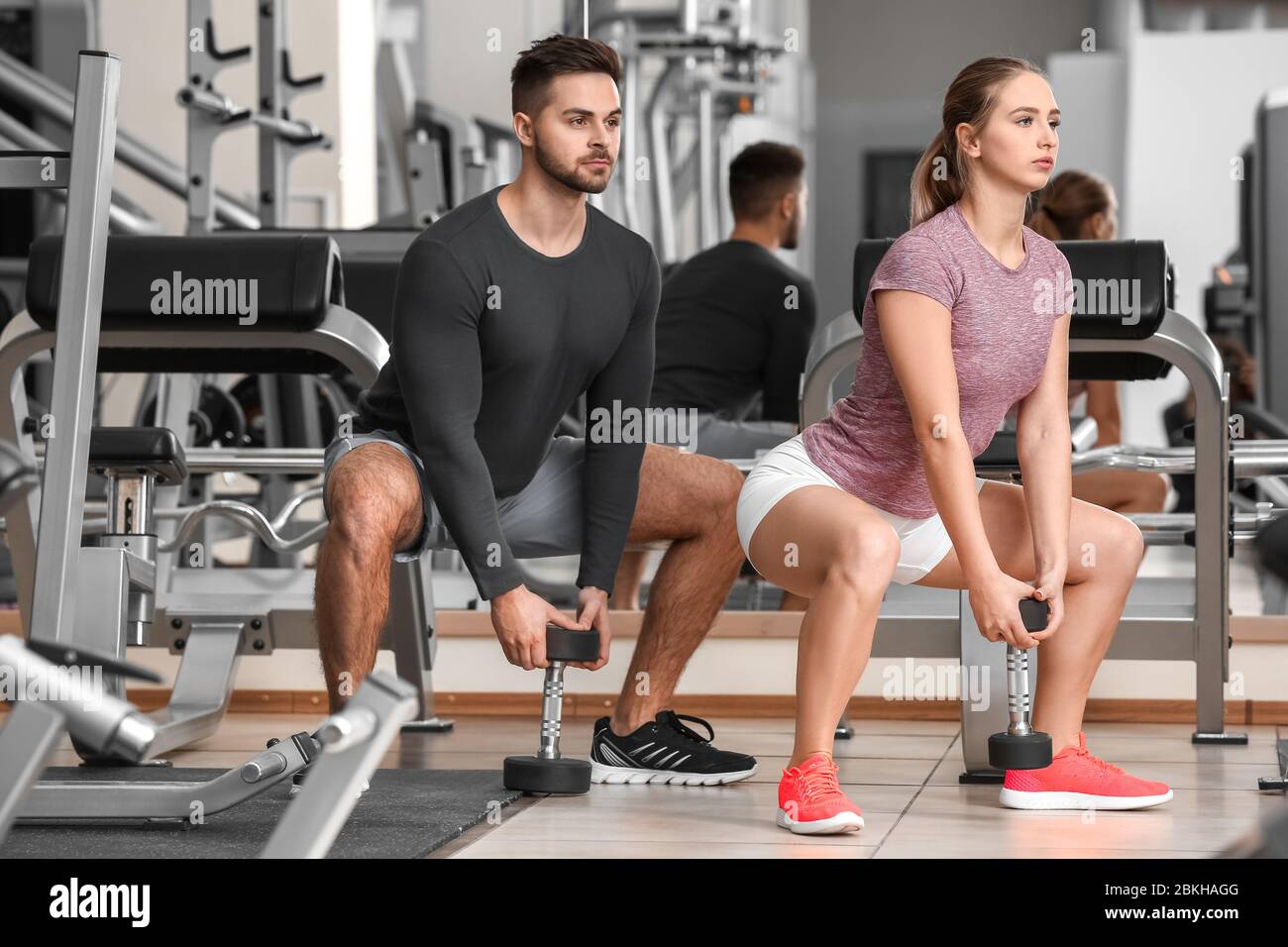 Sporty young couple training with dumbbells in gym Stock Photo - Alamy