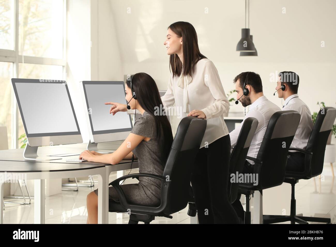 Professional technical support agent teaching young people in office ...