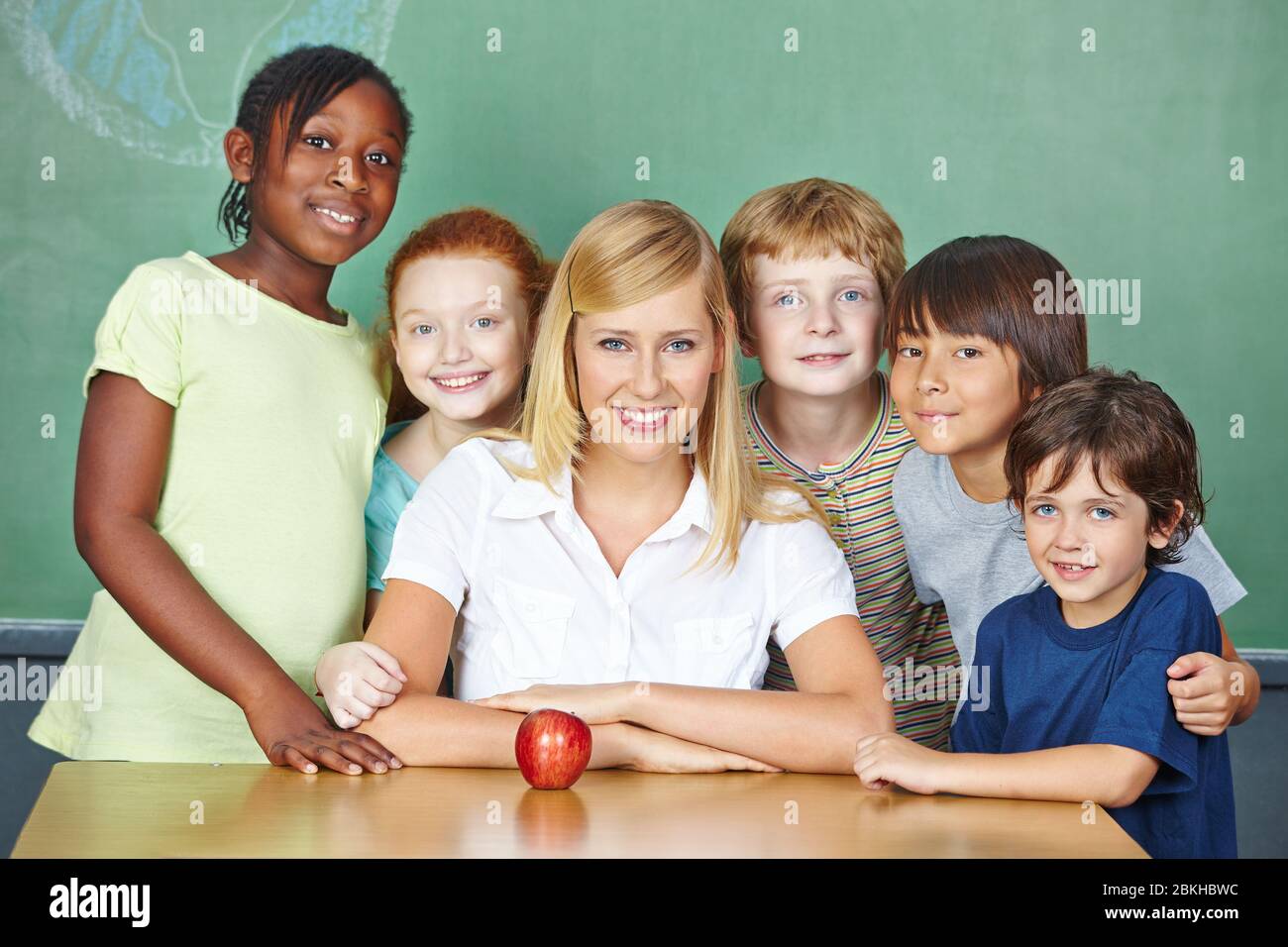 Smiling teacher with a group of her students at school Stock Photo