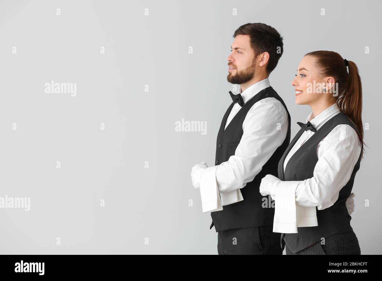 Male and female waiters on grey background Stock Photo - Alamy