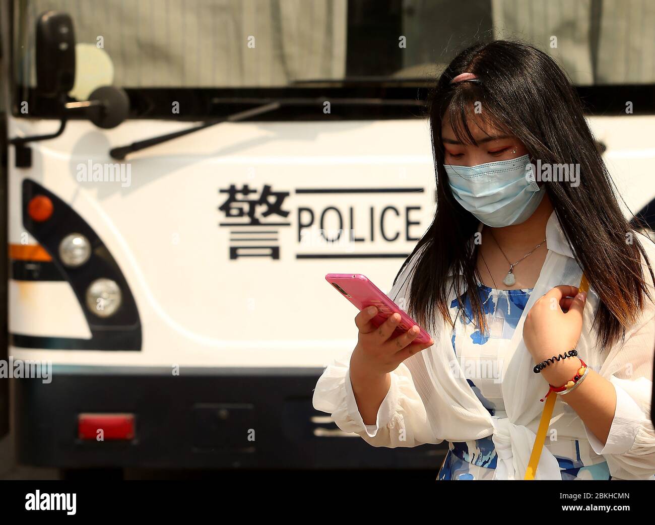 Beijing, China. 04th May, 2020. A Chinese woman uses her phone next to a mobile police command bus as the government announced the Covid-19 threat is basically over in Beijing on Monday, May 4, 2020. China's capital lowered its emergency response to the novel coronavirus pandemic from the top level to the second level, the 'latest sign of social order restoration as the epidemic conditions have been eased,' according to state media. Photo by Stephen Shaver/UPI Credit: UPI/Alamy Live News Stock Photo