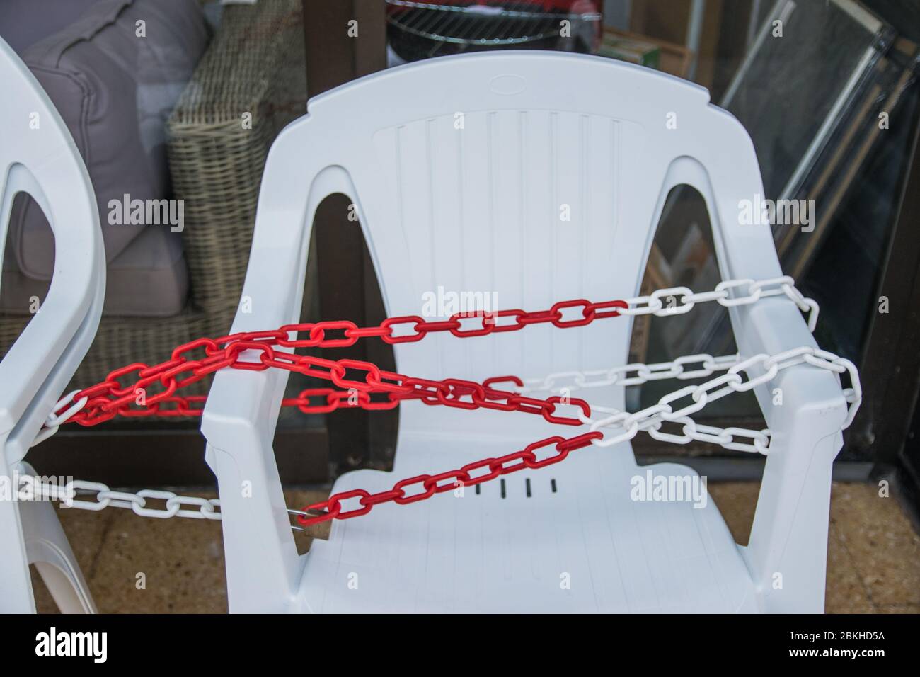 White plastic chairs with chain in summer cafe near the shop. Stock Photo