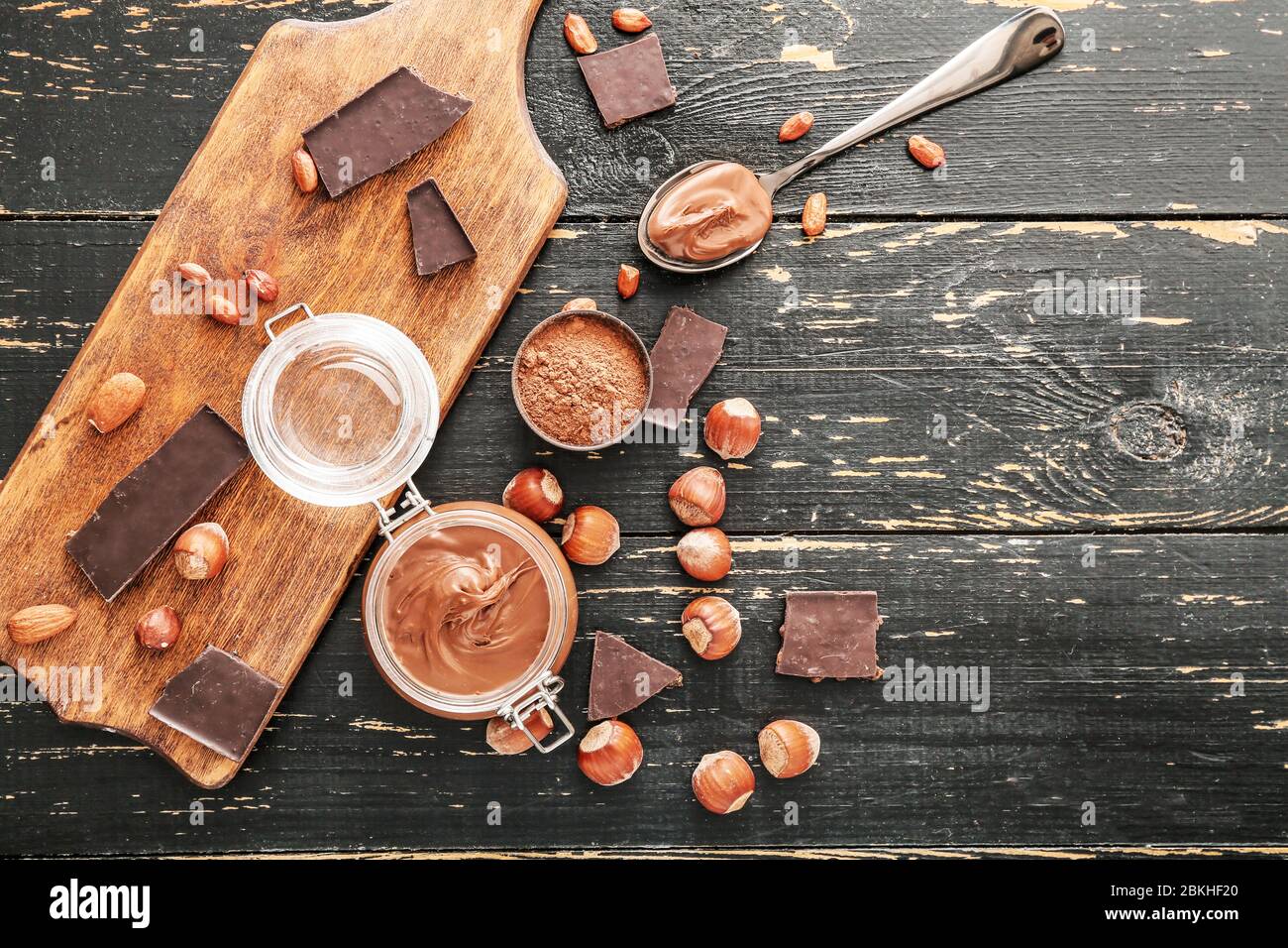 Jar with tasty chocolate paste and hazelnuts on table Stock Photo