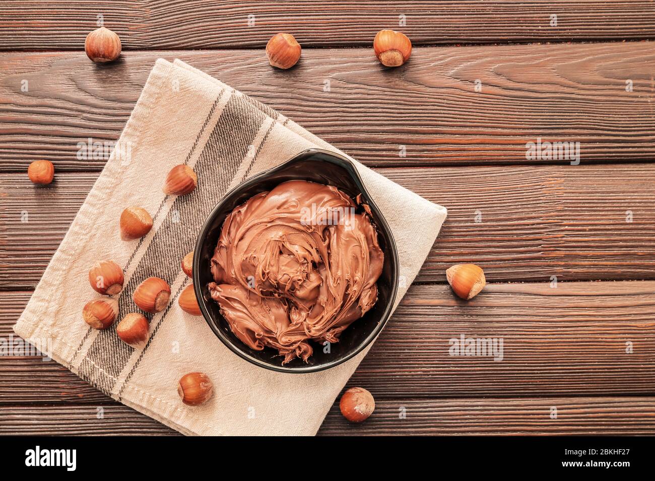 Bowl with tasty chocolate paste and hazelnuts on table Stock Photo