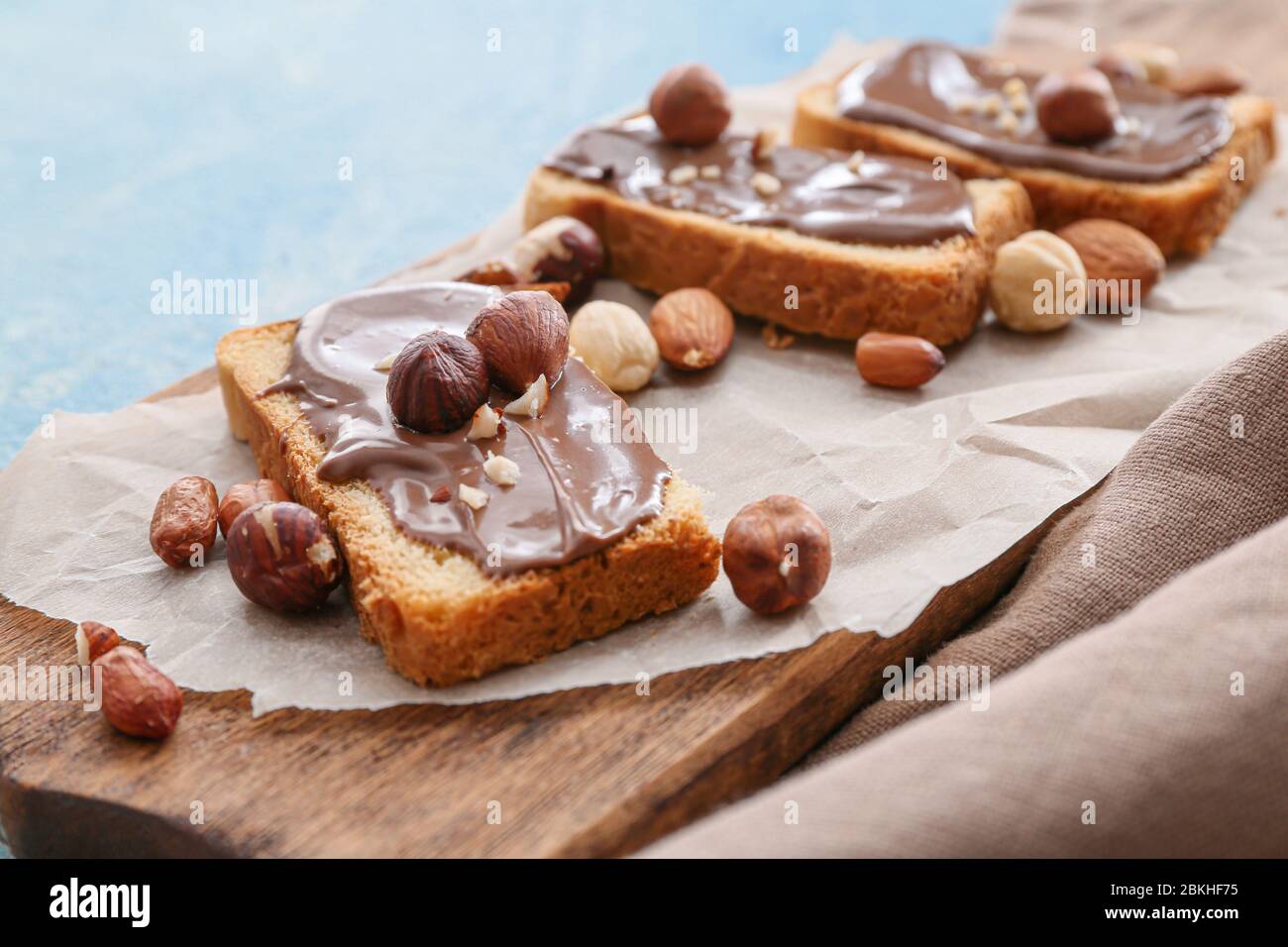 Fresh bread and chocolate paste and nuts on board, closeup Stock Photo